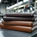 Stapel personalisierter Versicherungsordner mit geprägten Firmenlogos auf Produktionstisch, Druckausrüstung im Hintergrund