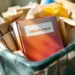 Versicherungsordner mit buntem Markencover in transparentem Recyclingbehälter mit Papiermaterialien und Bürodokumenten