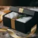 Luxuriöse schwarze Weihnachts-Geschenkbox mit Goldband, Tannenzweig und Seidenpapier auf rustikalem Holztisch mit leichtem Schnee.