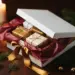 Luxuriöse weiße Geschenkbox mit rotem Seidenpapier, Satinband, Tannenzweigen und goldenen Weihnachtskugeln auf dunklem Walnussholz.