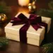 Luxuriöse Weihnachtsgeschenkbox mit burgunderroter Samtschleife, umgeben von Tannenzweigen und Goldkugeln im Kerzenlicht.