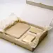 Geöffnete Onboarding-Box mit Notizbuch, Geschenkkarte und Seidenpapier in Champagner- und Goldtönen auf weißer Oberfläche.