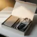 Geöffnete Onboarding-Willkommensbox mit Notizbuch, Stift und gefalteten Corporate Gifts auf weißem Schreibtisch in warmem Licht.