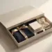 Hochwertiges Onboarding-Willkommenspaket mit geöffnetem Deckel, Markenmerchandise, Seidenpapier und Goldband auf weißem Untergrund.